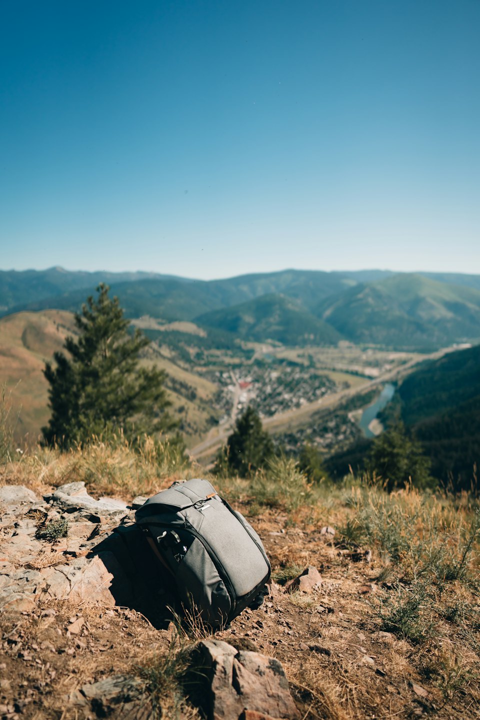 Grey hiking backpack sitting on a mountain peak overlooking a valley.