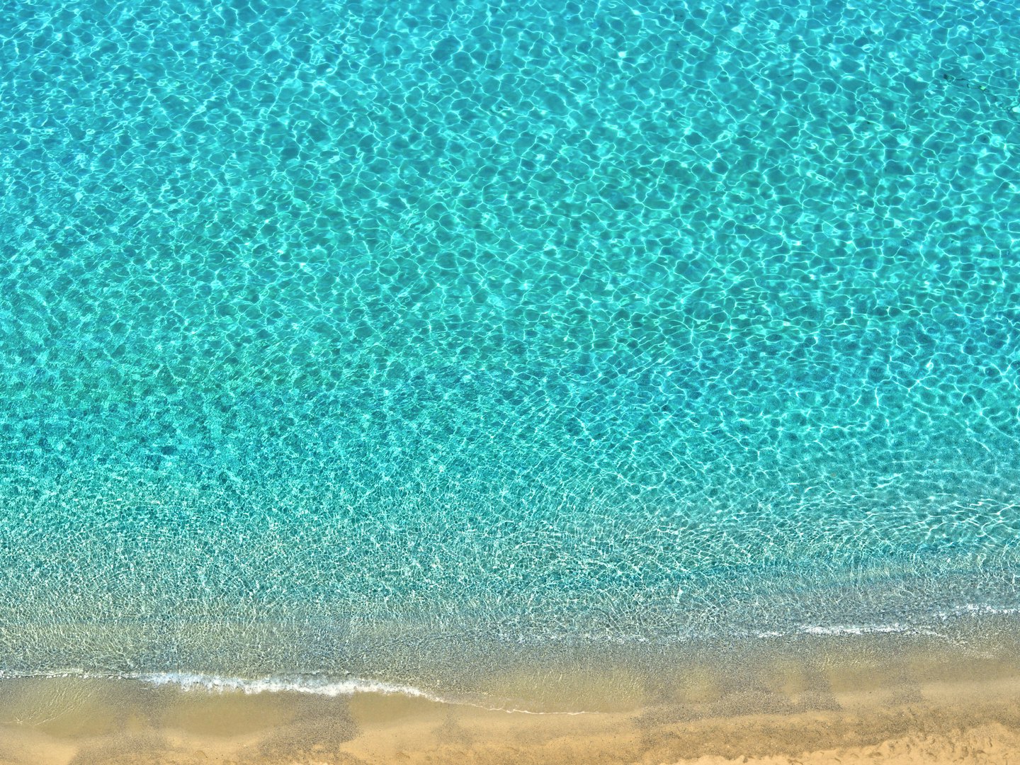 Gentle ocean waves wash onto a sandy beach.