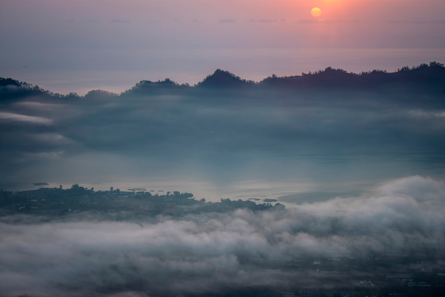 Mountain town sits nestled in a valley beneath misty peaks.