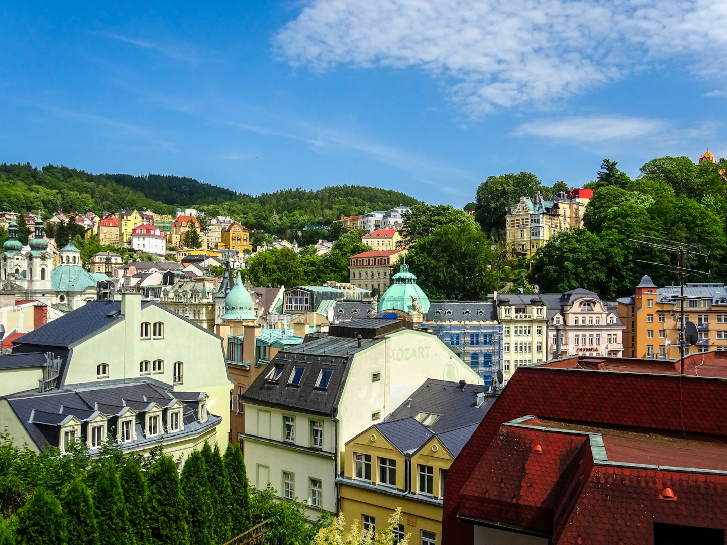 Colorful buildings nestle within a green hillside European town.